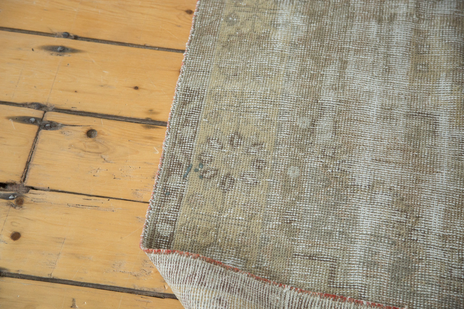 Close-up of distressed vintage Oushak rug pile with secured side in muted earth tones.